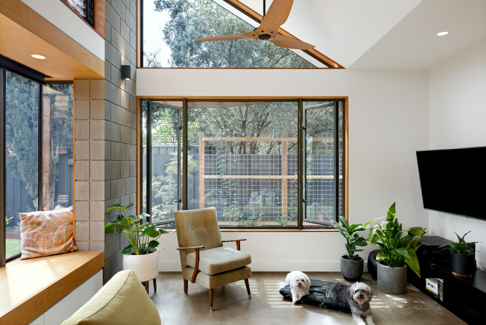 Small contemporary open plan living room in Melbourne with concrete flooring, a vaulted ceiling and brick walls.