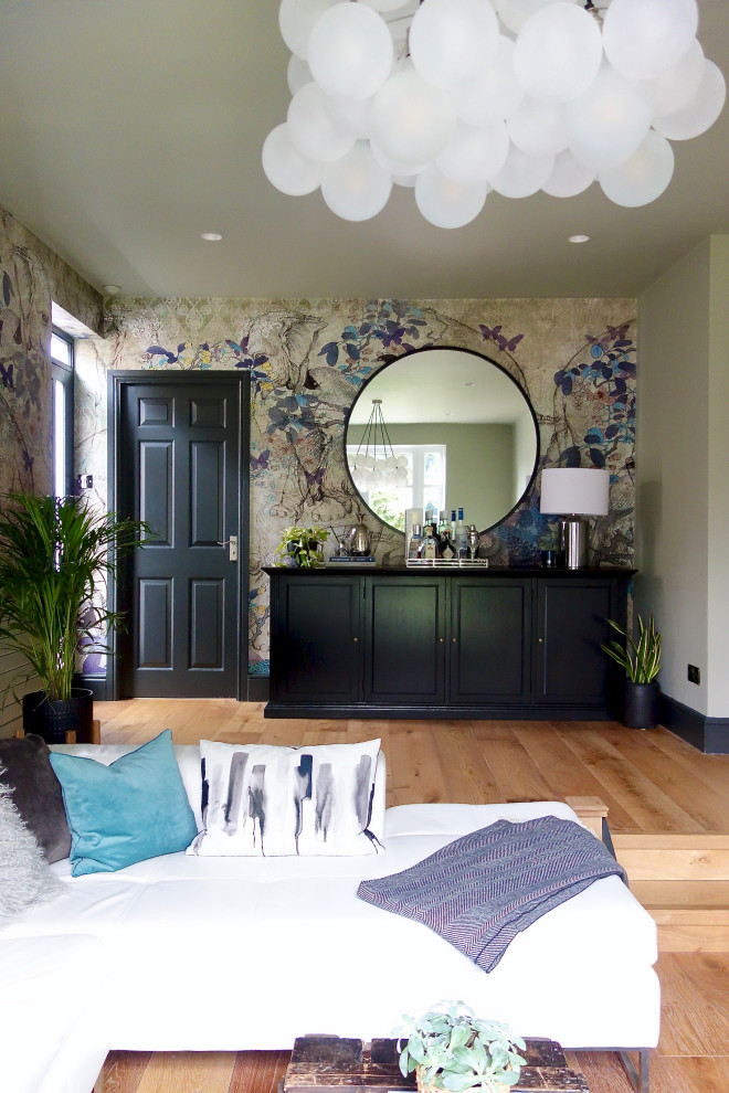 Mittelgroßes Stilmix Wohnzimmer mit Hausbar, grüner Wandfarbe, braunem Holzboden und TV-Wand in Sonstige