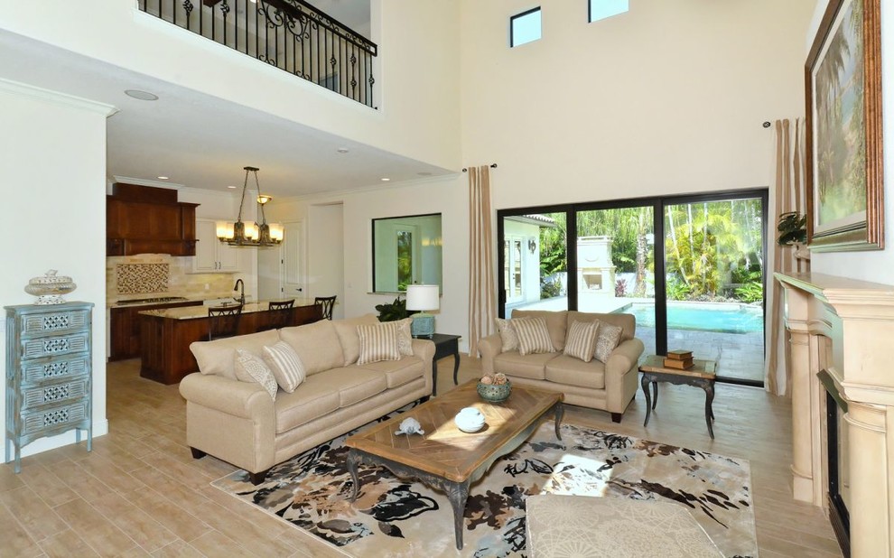 Mittelgroßes, Offenes Mediterranes Wohnzimmer mit beiger Wandfarbe, Porzellan-Bodenfliesen, Kamin und gefliester Kaminumrandung in Tampa