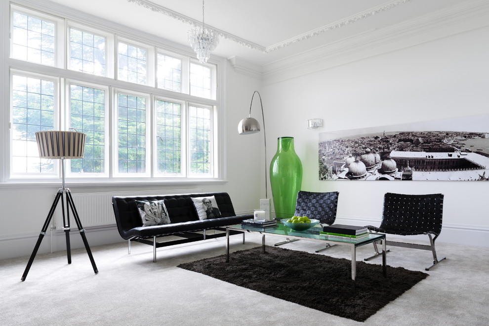Aménagement d'un salon contemporain avec une salle de réception, un mur blanc, moquette et canapé noir.