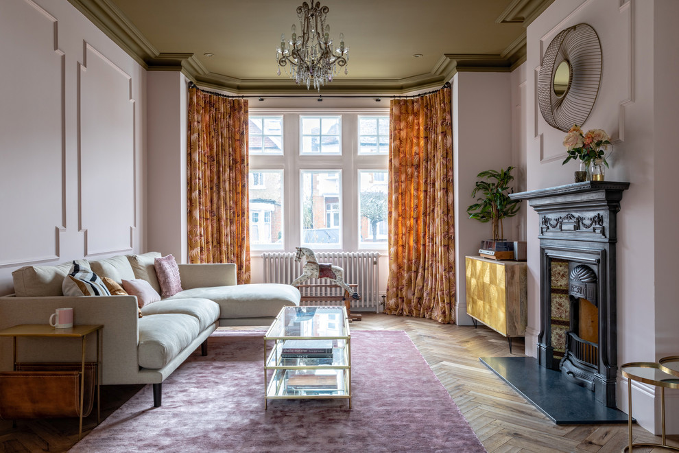 На фото: гостиная комната в викторианском стиле с светлым паркетным полом, стандартным камином и розовыми стенами без телевизора с