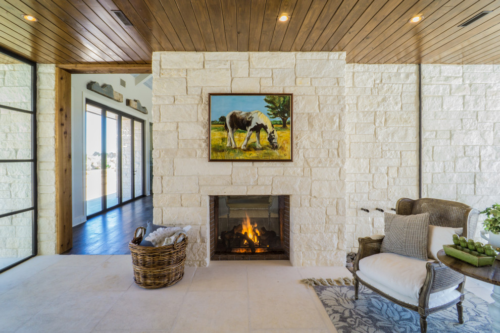 Mittelgroßes Landhaus Wohnzimmer mit Tunnelkamin, Kaminumrandung aus Stein, beigem Boden und Steinwänden in Austin