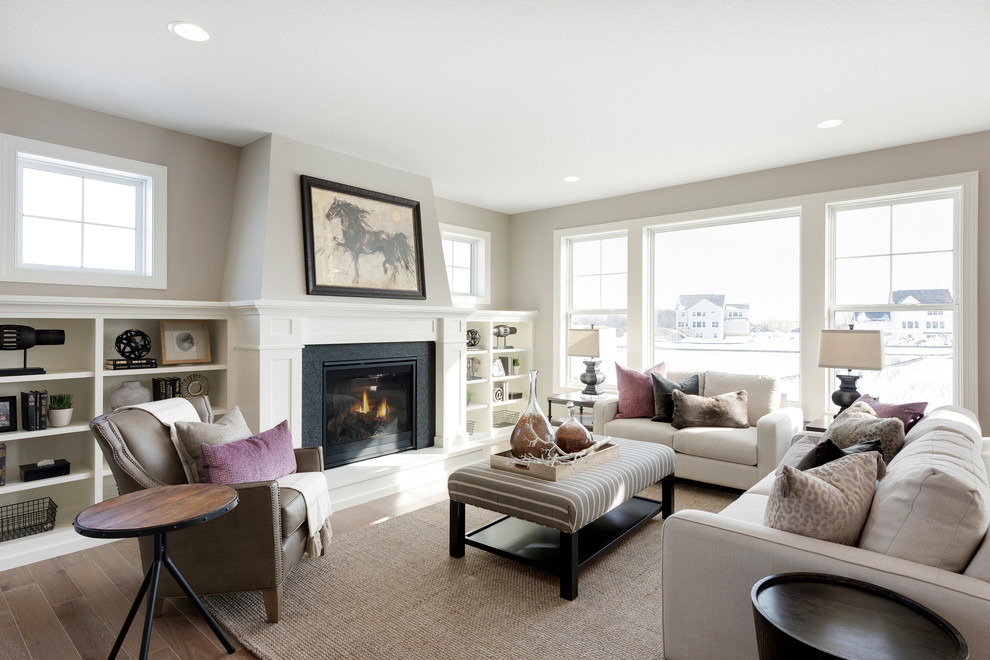 Idée de décoration pour un salon tradition avec un mur gris, un sol en bois brun, une cheminée standard et un sol marron.