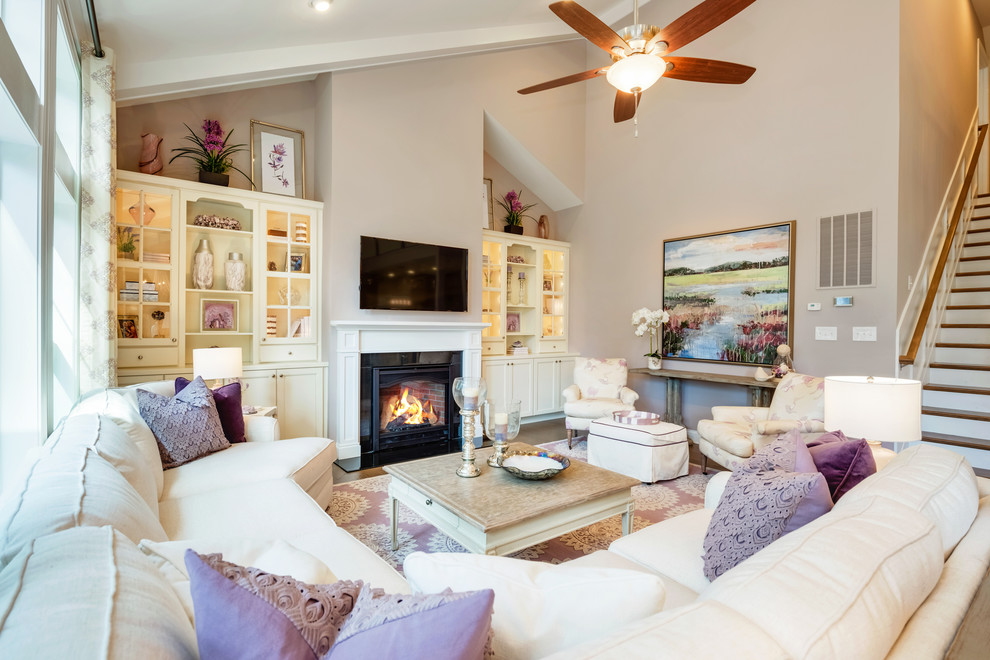 Exemple d'un salon romantique de taille moyenne et ouvert avec une salle de réception, un mur violet, un sol en bois brun, une cheminée standard, un manteau de cheminée en pierre, un téléviseur fixé au mur et un sol marron.