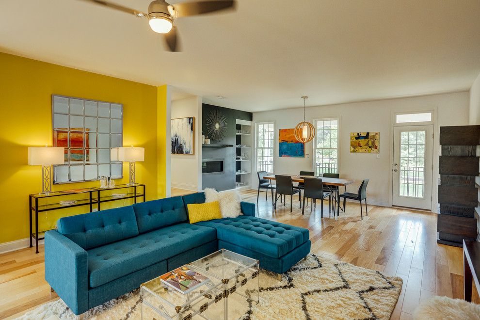 На фото: открытая гостиная комната:: освещение в современном стиле с желтыми стенами и горизонтальным камином