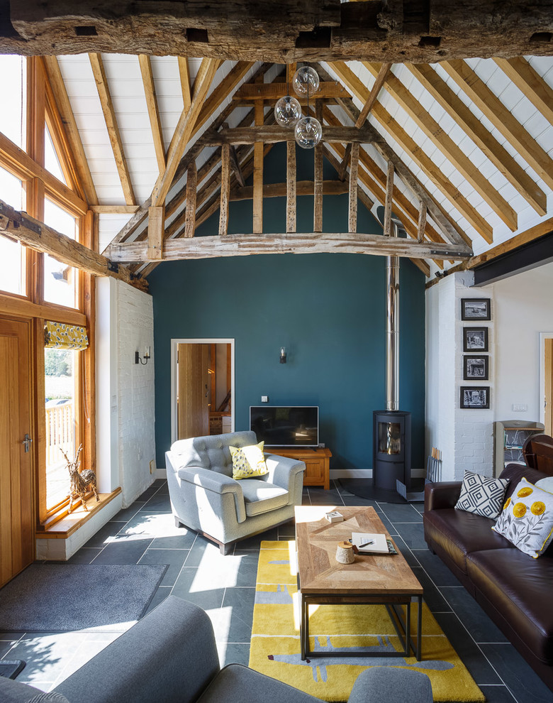This is an example of a rural grey and teal open plan living room in Essex with blue walls and grey floors.