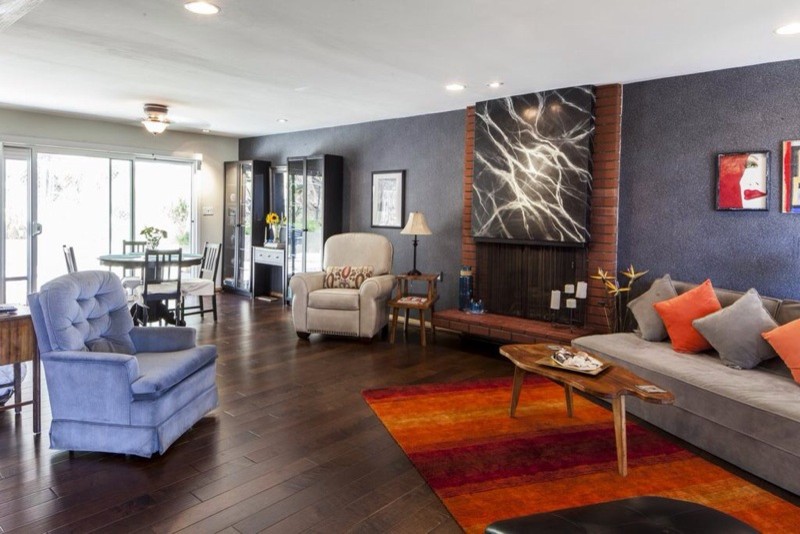 Offenes Eklektisches Wohnzimmer mit grauer Wandfarbe, braunem Holzboden und Kaminumrandung aus Backstein in Los Angeles