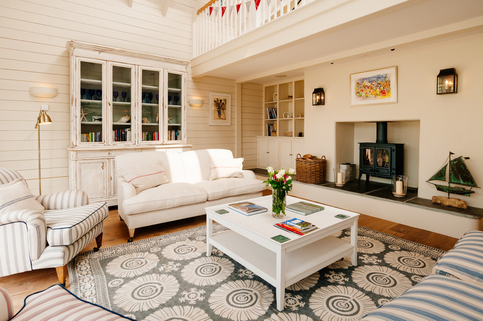 Esempio di un soggiorno stile marino con pareti bianche, pavimento in legno massello medio e stufa a legna