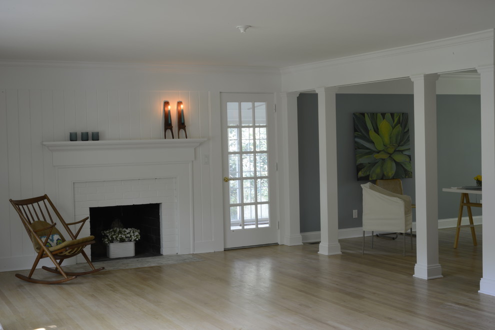Mittelgroßes, Fernseherloses, Offenes Maritimes Wohnzimmer mit weißer Wandfarbe, hellem Holzboden, Kamin, Kaminumrandung aus Holz und beigem Boden in New York