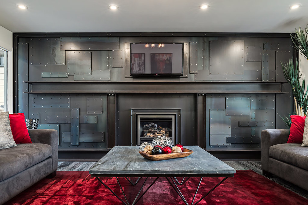 Inspiration for a large industrial enclosed carpeted living room remodel in Calgary with black walls, a standard fireplace, a metal fireplace and a wall-mounted tv