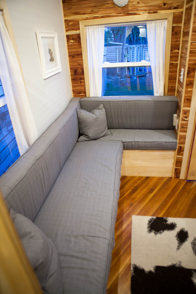 Idee per un piccolo soggiorno chic aperto con pareti grigie, pavimento in legno massello medio, stufa a legna e cornice del camino in metallo