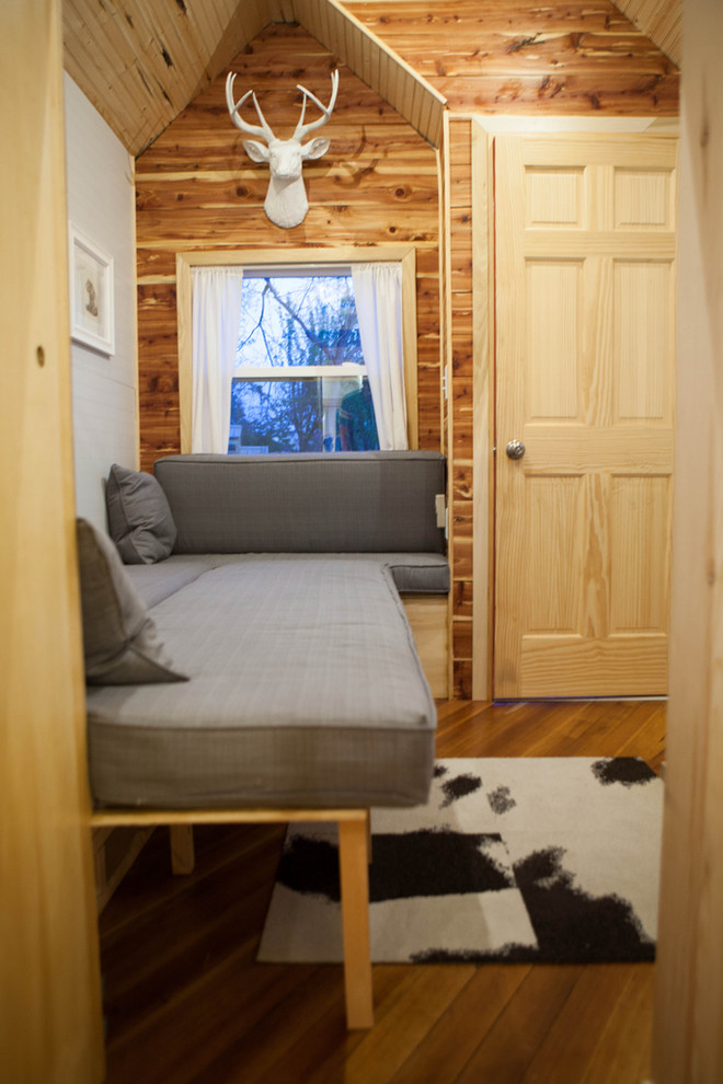 На фото: маленькая открытая гостиная комната в классическом стиле с серыми стенами, паркетным полом среднего тона, печью-буржуйкой и фасадом камина из металла без телевизора для на участке и в саду