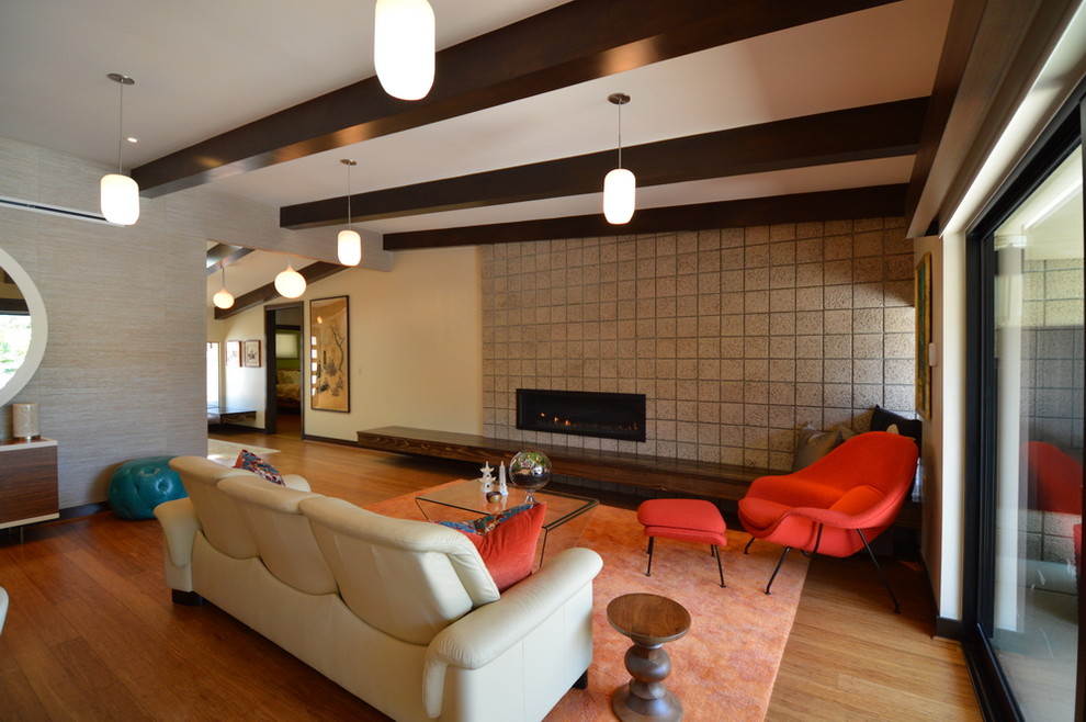 Großes, Offenes Mid-Century Wohnzimmer mit bunten Wänden, braunem Holzboden, Kamin und Kaminumrandung aus Beton in Los Angeles