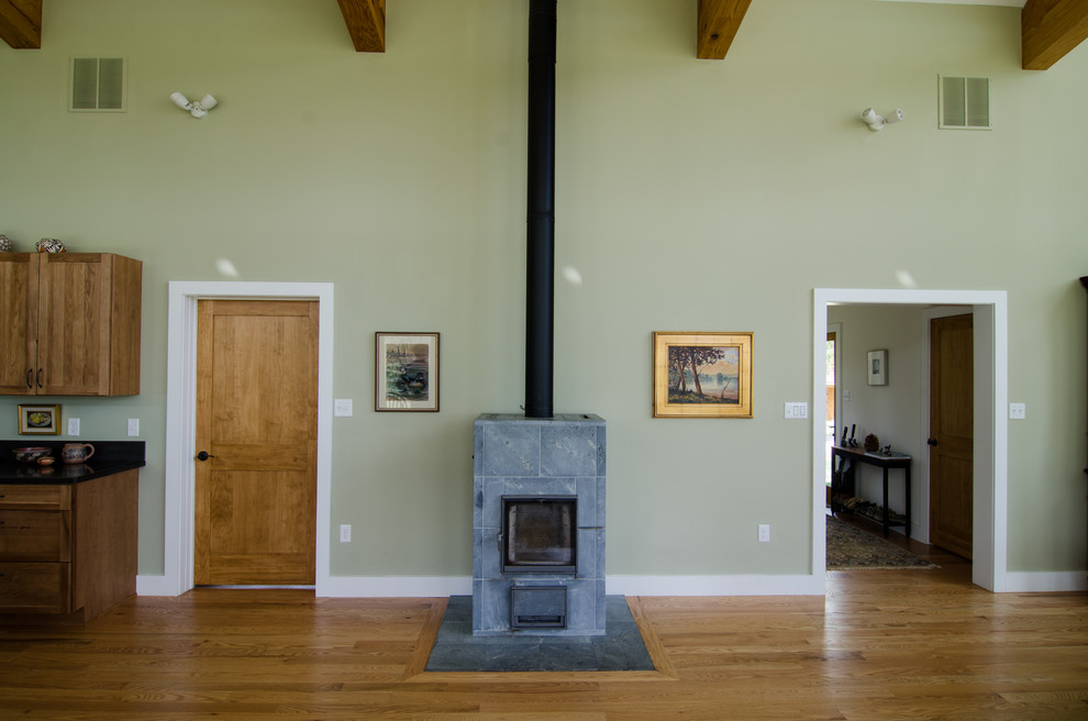 Imagen de salón abierto minimalista de tamaño medio con paredes beige, suelo de madera en tonos medios, estufa de leña y marco de chimenea de piedra