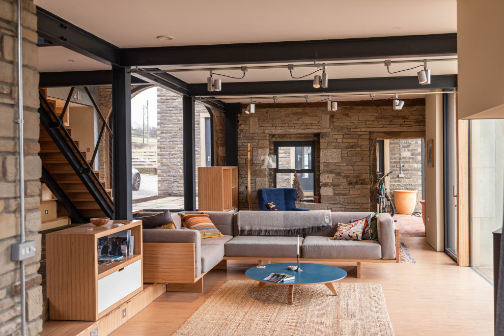 Mittelgroßes, Offenes Modernes Wohnzimmer mit braunem Holzboden, braunem Boden und Steinwänden in Sonstige