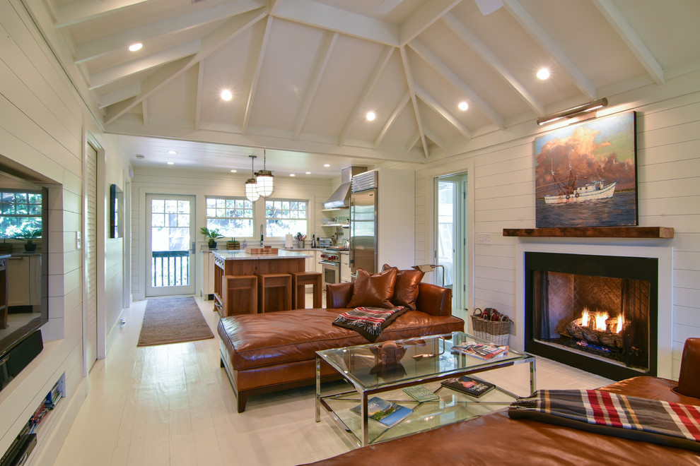 This is an example of a small coastal open plan living room in Charleston with white walls, light hardwood flooring, a standard fireplace and white floors.