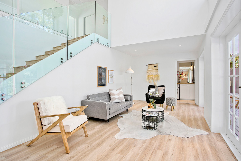 Idéer för minimalistiska vardagsrum, med vita väggar och ljust trägolv