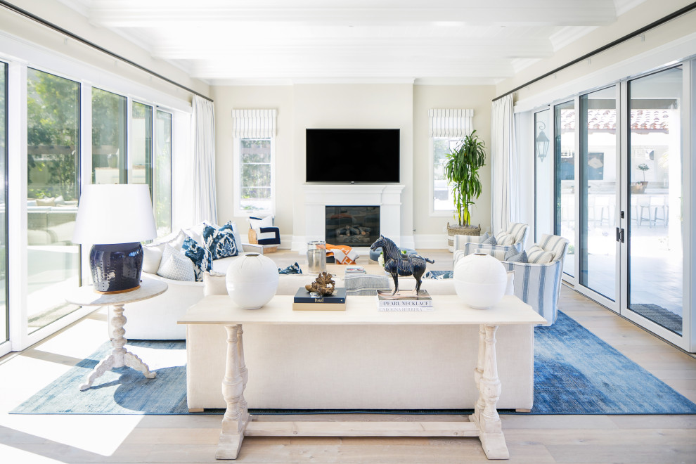 Inspiration for a coastal open concept medium tone wood floor, brown floor and exposed beam living room remodel in Orange County with beige walls, a standard fireplace and a wall-mounted tv