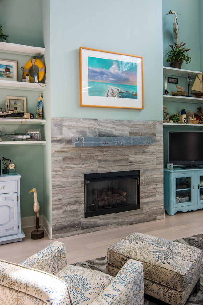 ジャクソンビルにある高級な中くらいなビーチスタイルのおしゃれなリビング (青い壁、淡色無垢フローリング、標準型暖炉、タイルの暖炉まわり、据え置き型テレビ) の写真