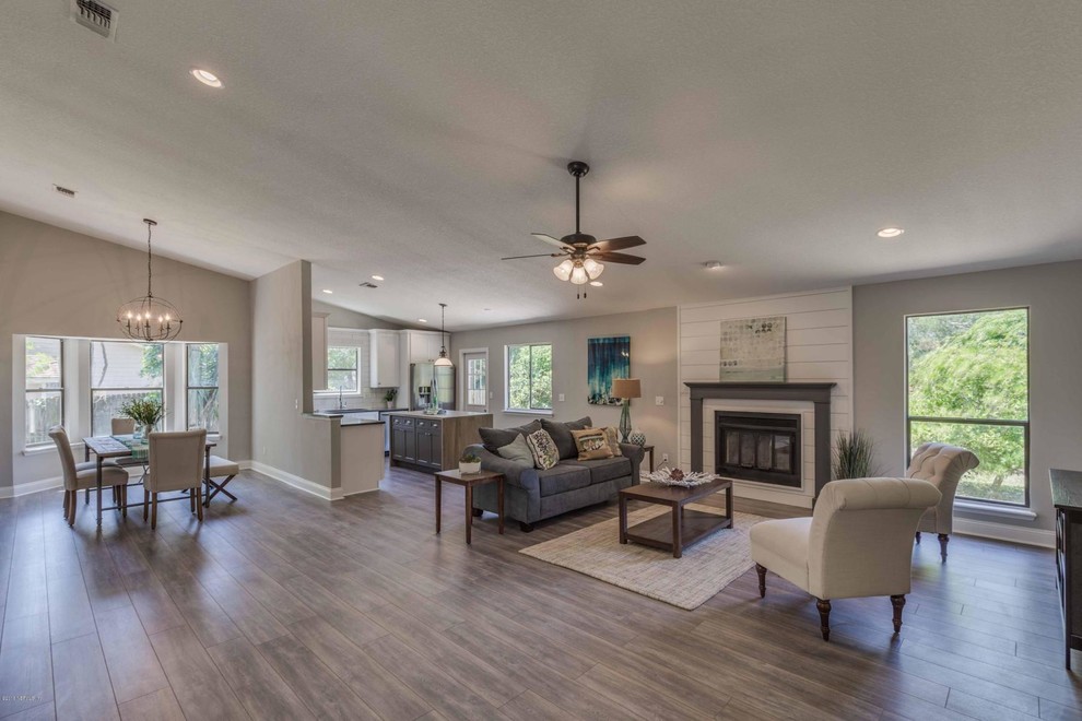 Transitional open concept medium tone wood floor and gray floor living room photo in Jacksonville with gray walls, a standard fireplace and a wood fireplace surround