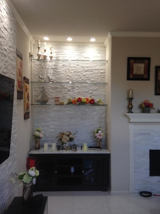 Modelo de salón tradicional de tamaño medio con paredes beige, suelo de baldosas de porcelana, chimenea lineal, marco de chimenea de piedra y televisor colgado en la pared