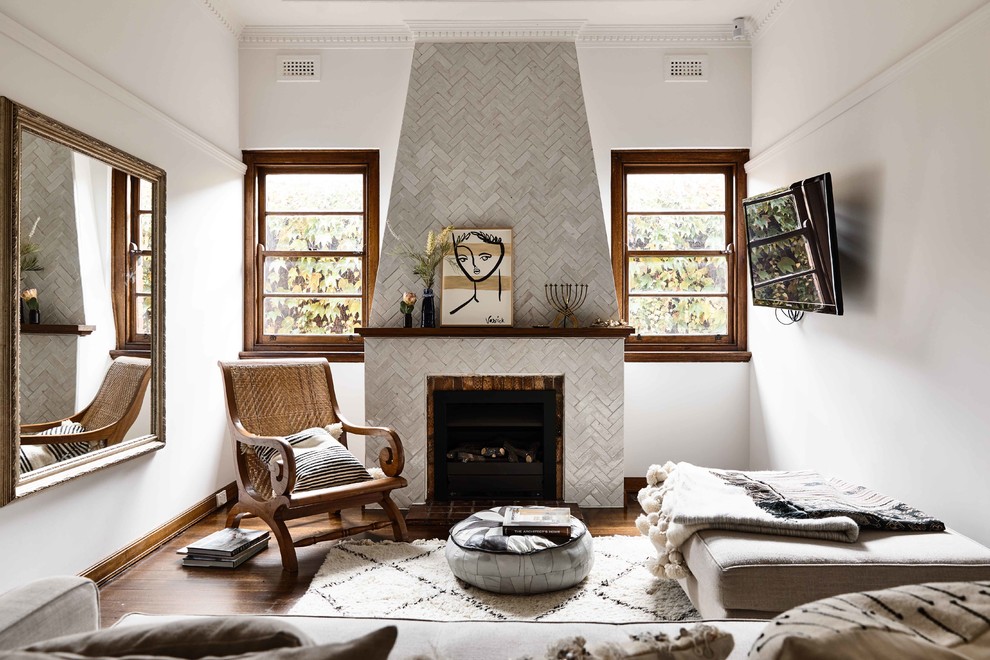 Exempel på ett medelhavsstil separat vardagsrum, med vita väggar, mörkt trägolv, en standard öppen spis, en spiselkrans i trä, en väggmonterad TV och brunt golv