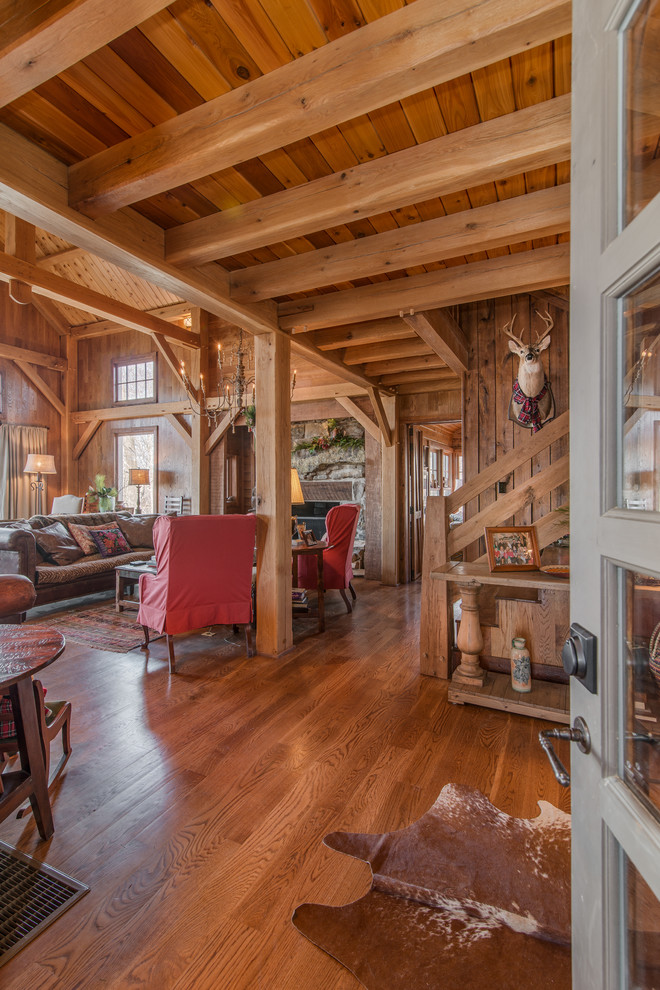Aménagement d'un grand salon montagne ouvert avec un sol en bois brun, une cheminée standard et un manteau de cheminée en pierre.
