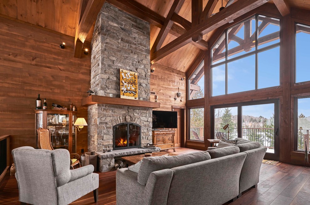 Inspiration for a medium sized rustic open plan living room in Montreal with brown walls, dark hardwood flooring, a stone fireplace surround, a freestanding tv, brown floors and a standard fireplace.