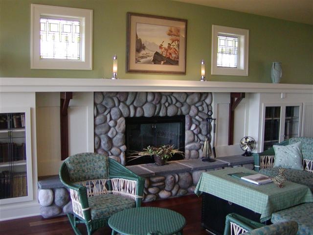 Immagine di un soggiorno tradizionale di medie dimensioni con pareti verdi, pavimento in legno massello medio, camino classico e cornice del camino in pietra