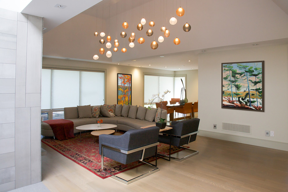 На фото: большая открытая гостиная комната в современном стиле с бежевыми стенами, светлым паркетным полом, стандартным камином, бежевым полом и фасадом камина из камня без телевизора