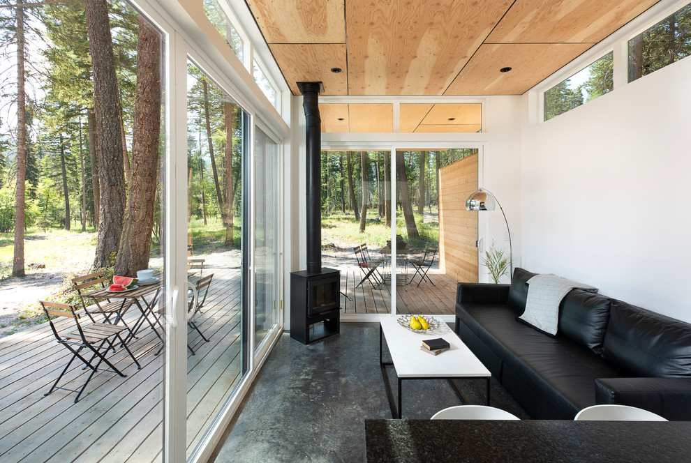 Идея дизайна: маленькая открытая гостиная комната в стиле рустика с белыми стенами, бетонным полом, печью-буржуйкой и серым полом для на участке и в саду