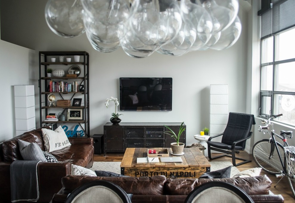 Immagine di un soggiorno bohémian stile loft con parquet chiaro e TV a parete
