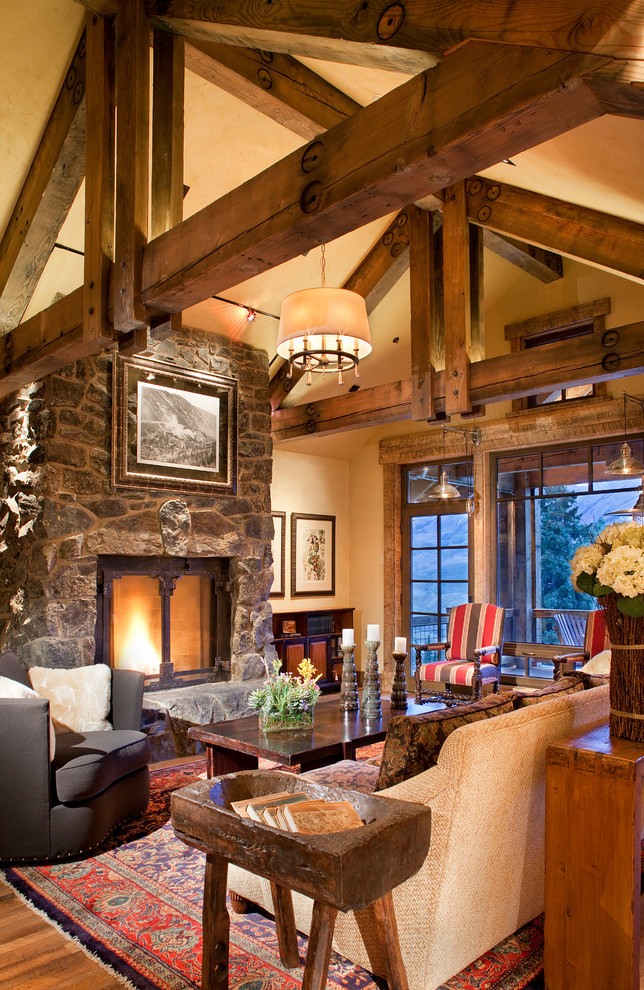 Living room - rustic open concept medium tone wood floor living room idea in Denver with beige walls, a standard fireplace and a stone fireplace