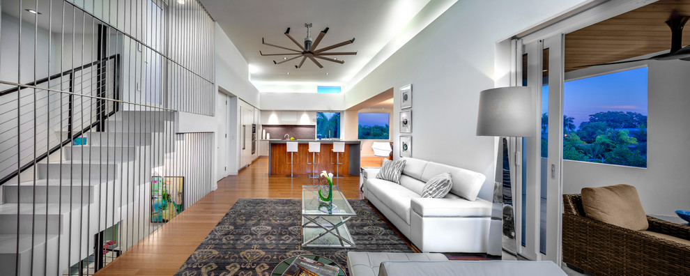 Esempio di un soggiorno contemporaneo aperto con pareti bianche, pavimento in bambù e TV a parete