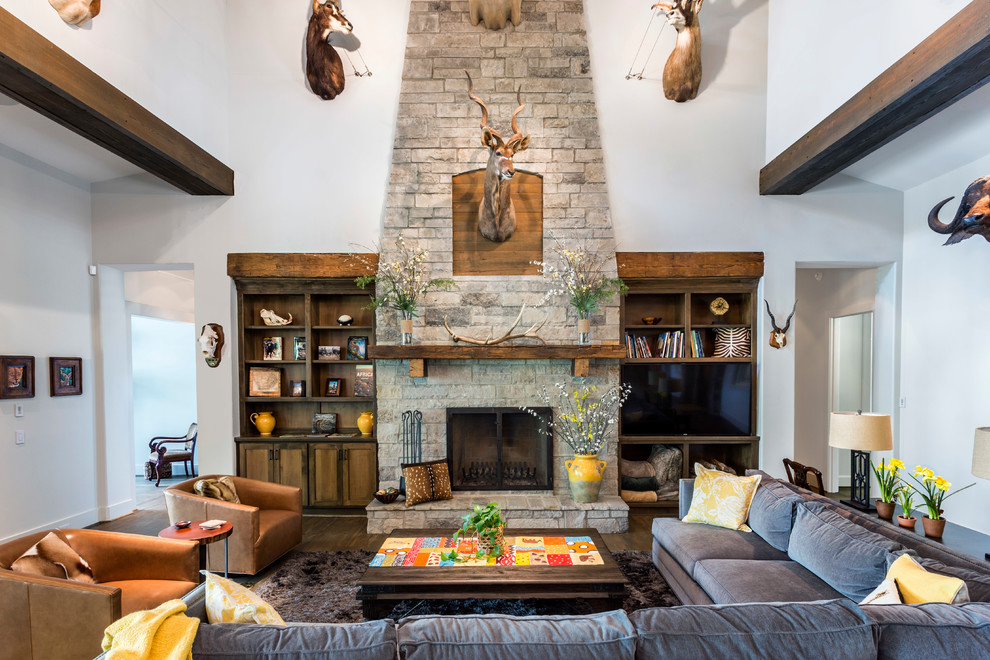 Inspiration for a rustic dark wood floor and brown floor living room remodel in Houston with white walls, a standard fireplace, a stone fireplace and a media wall