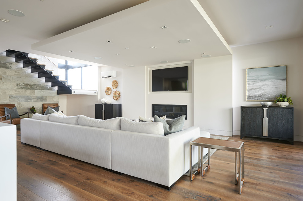 Aménagement d'un grand salon contemporain avec un mur blanc, un sol en bois brun et un sol marron.