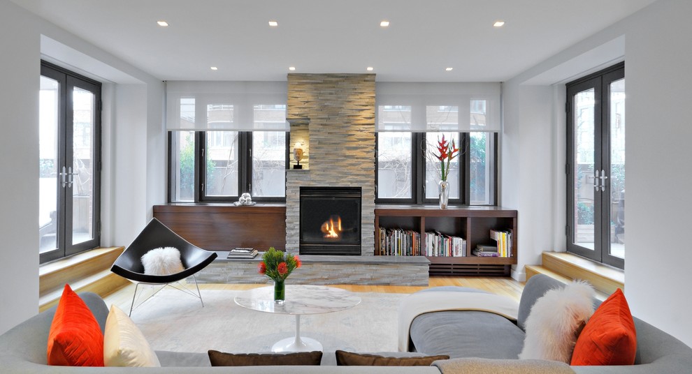 Modernes Wohnzimmer mit braunem Holzboden, Kamin und Kaminumrandung aus Stein in New York