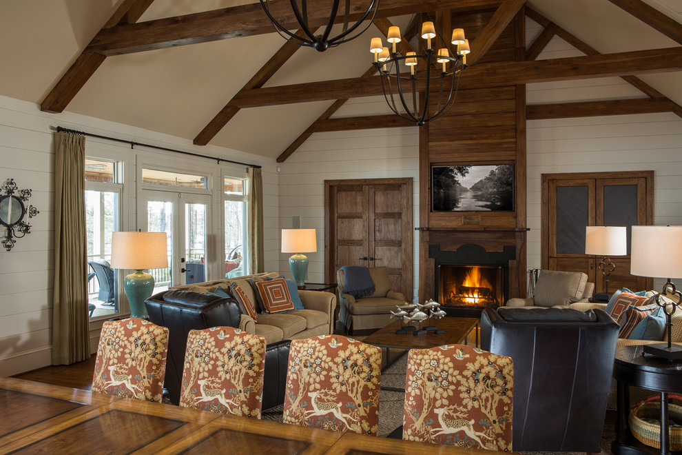 Inspiration for a large farmhouse open concept medium tone wood floor, brown floor, vaulted ceiling and shiplap wall living room remodel in Raleigh with white walls, a standard fireplace, a wood fireplace surround and a wall-mounted tv