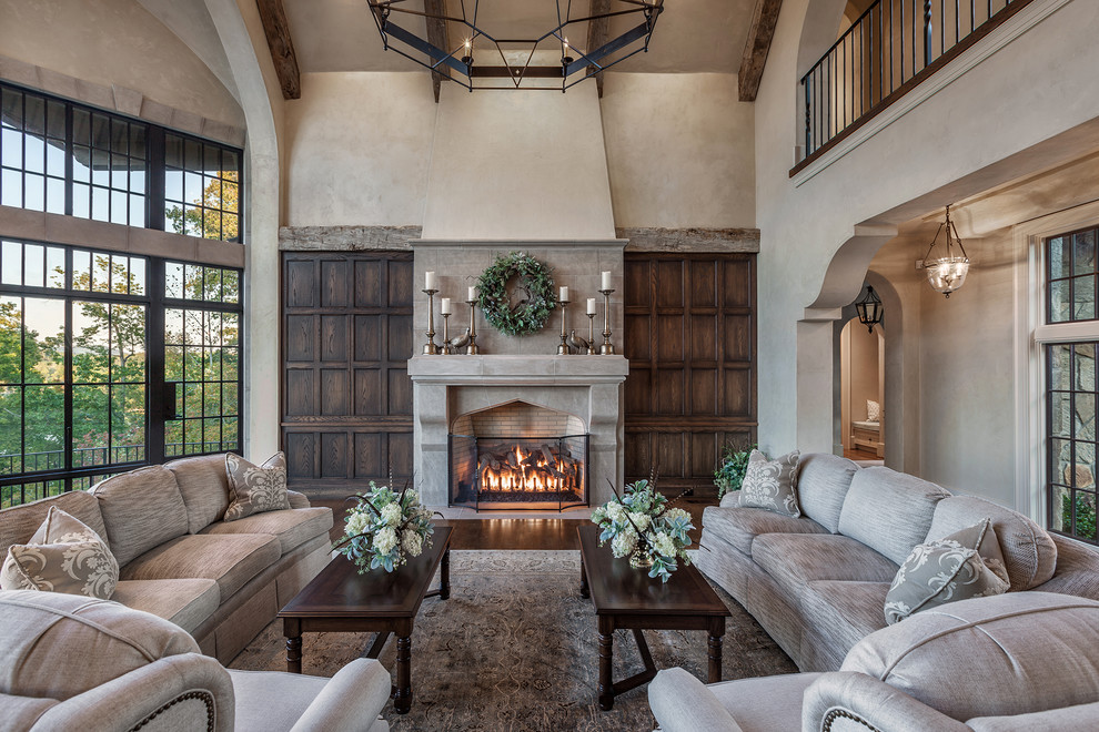 Photo of a large mediterranean open plan living room in Other with beige walls, medium hardwood flooring, a stone fireplace surround, a standard fireplace, a concealed tv and beige floors.