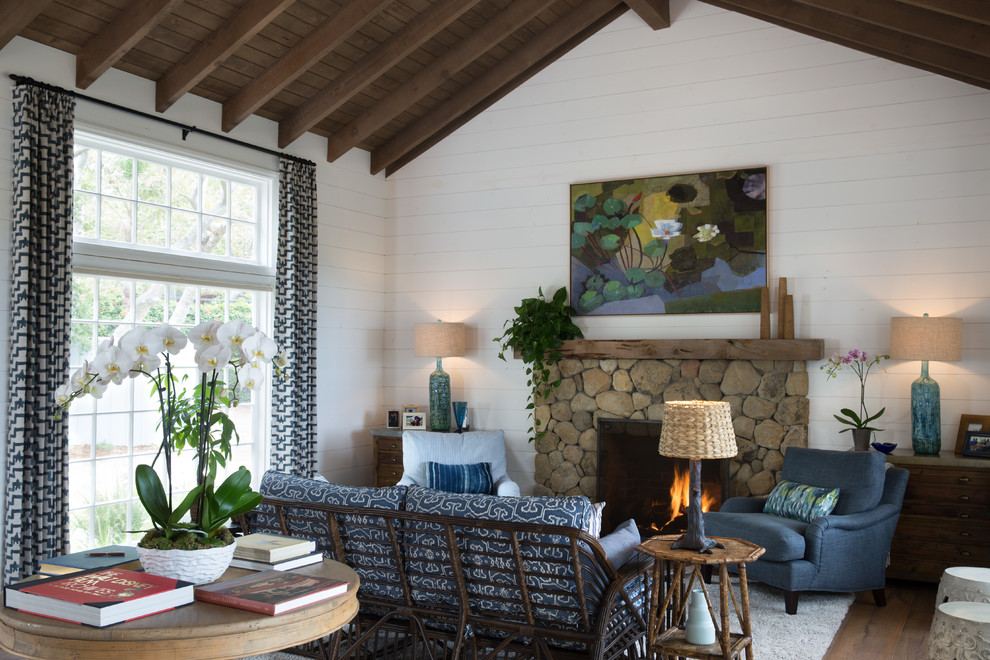 Diseño de salón de estilo de casa de campo con paredes blancas, suelo de madera en tonos medios, todas las chimeneas, marco de chimenea de piedra y suelo marrón