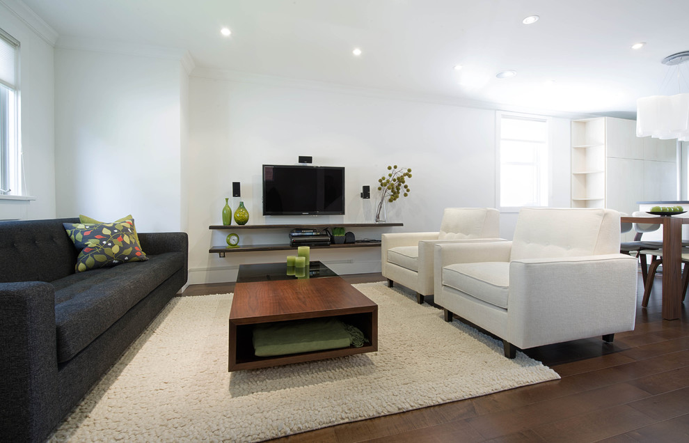 Immagine di un soggiorno minimalista con pareti bianche, parquet scuro e TV a parete