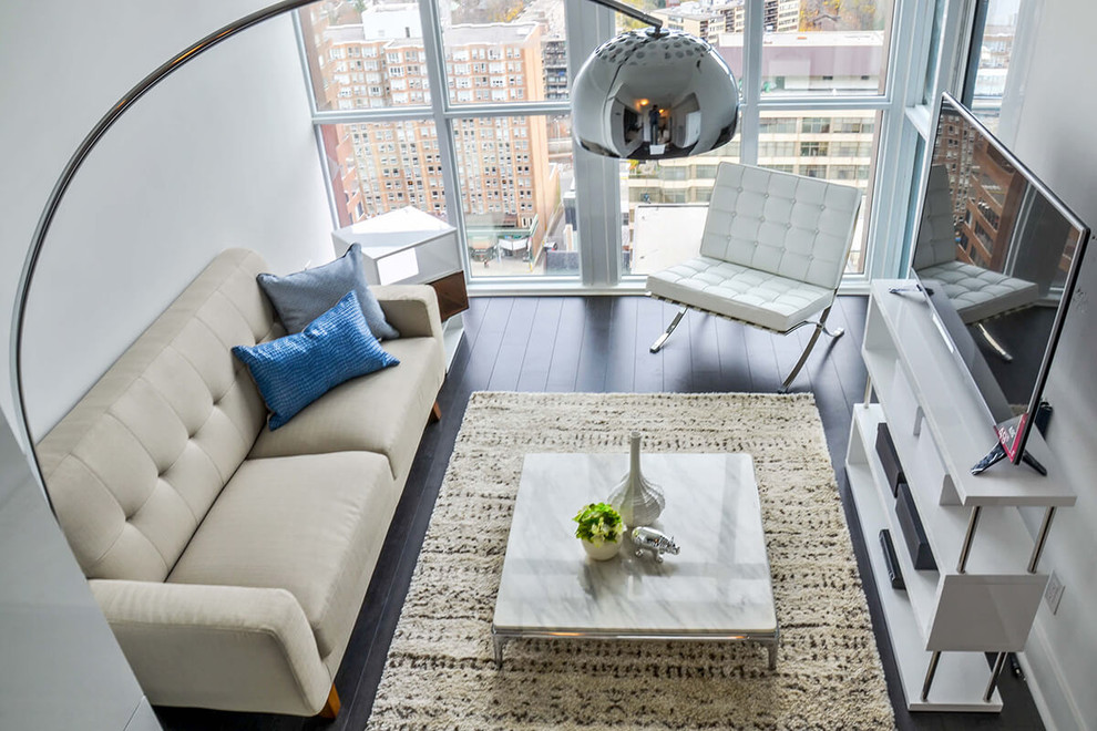Example of a small minimalist loft-style dark wood floor living room design in Toronto with white walls and no fireplace