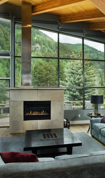 Inspiration pour un grand salon design ouvert avec une salle de réception, un mur gris, parquet clair, une cheminée standard, un manteau de cheminée en pierre et un sol marron.