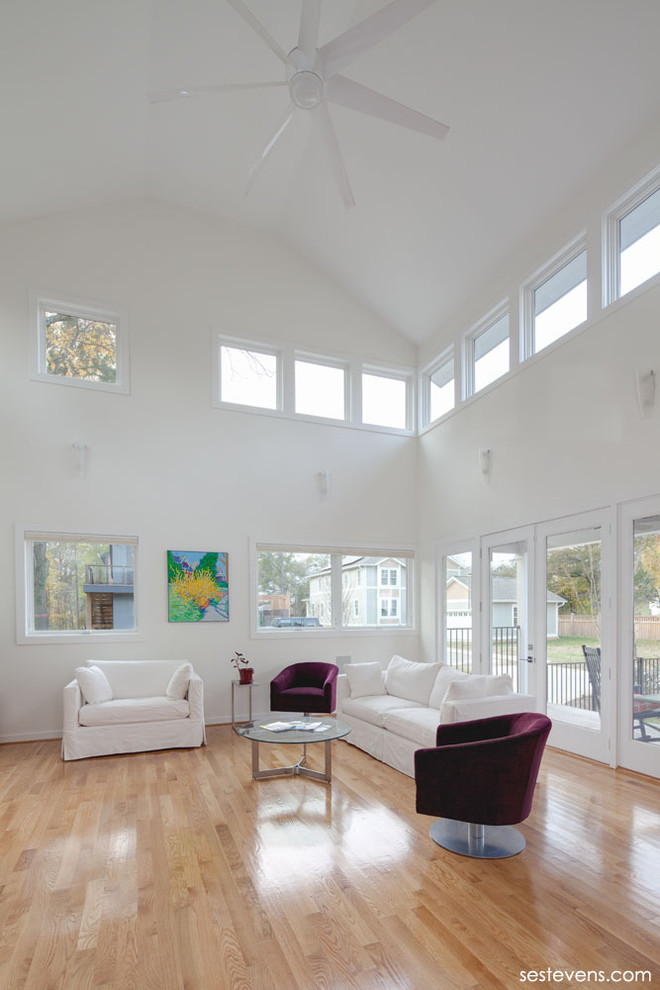Example of a large trendy formal and open concept light wood floor living room design in Raleigh with white walls and no fireplace
