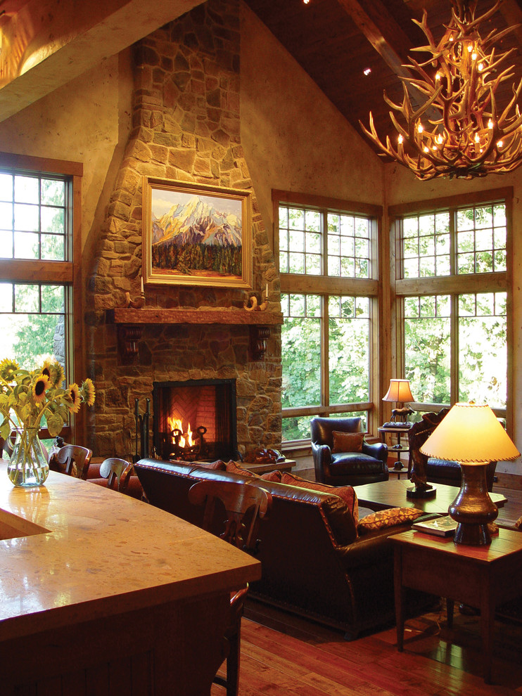 Imagen de salón tradicional con paredes marrones, suelo de madera en tonos medios, todas las chimeneas y marco de chimenea de piedra
