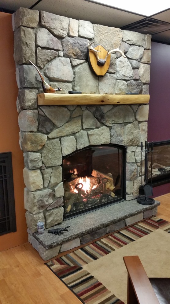 ポートランド(メイン)にある高級な中くらいなラスティックスタイルのおしゃれなリビング (標準型暖炉、石材の暖炉まわり) の写真