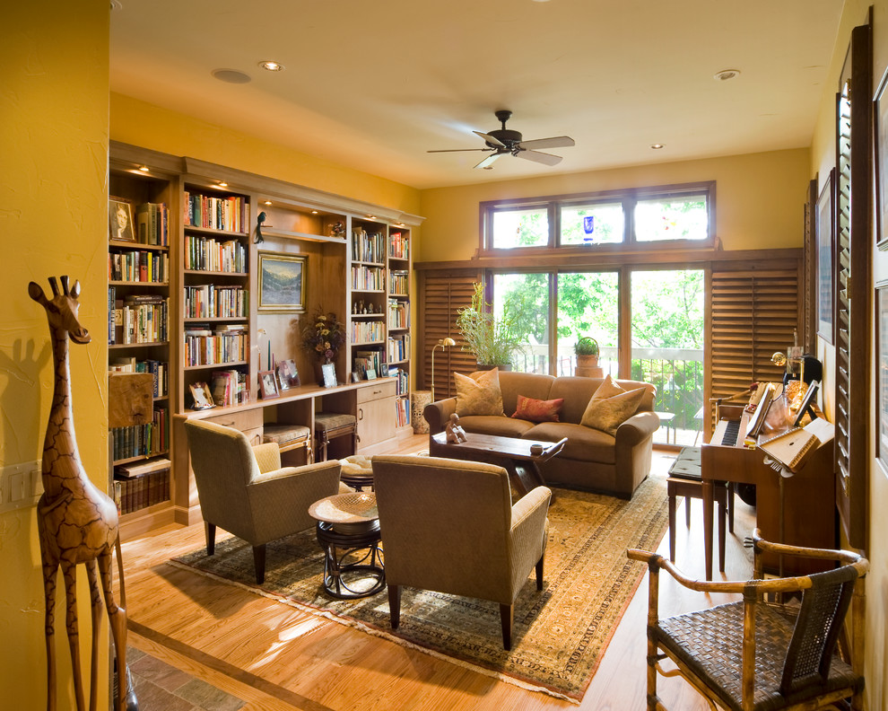 Exemple d'un grand salon chic ouvert avec une bibliothèque ou un coin lecture, un mur jaune, parquet clair, aucune cheminée, aucun téléviseur et un sol beige.