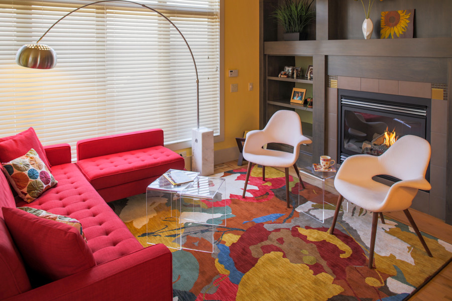 На фото: гостиная комната в современном стиле с желтыми стенами, стандартным камином и фасадом камина из плитки с