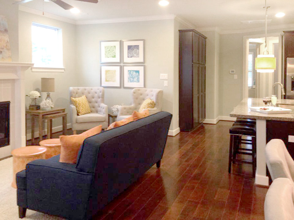 Offenes, Fernseherloses Klassisches Wohnzimmer mit Kamin, grauer Wandfarbe, braunem Holzboden und verputzter Kaminumrandung in Houston