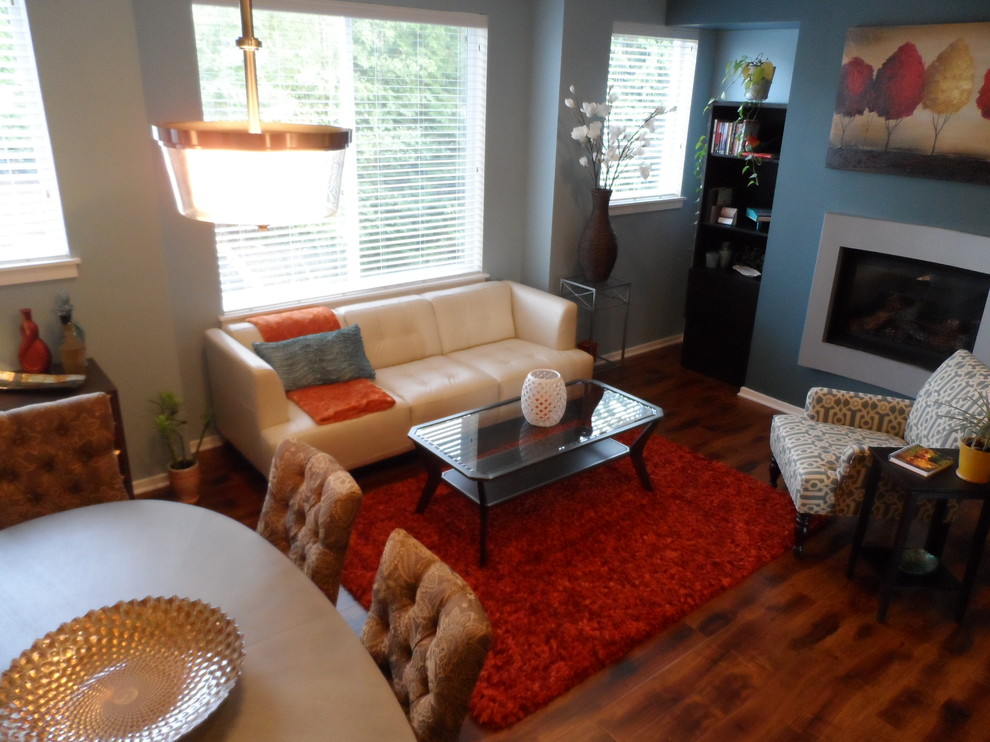 Example of a small trendy medium tone wood floor living room design in Seattle with a hanging fireplace and a metal fireplace